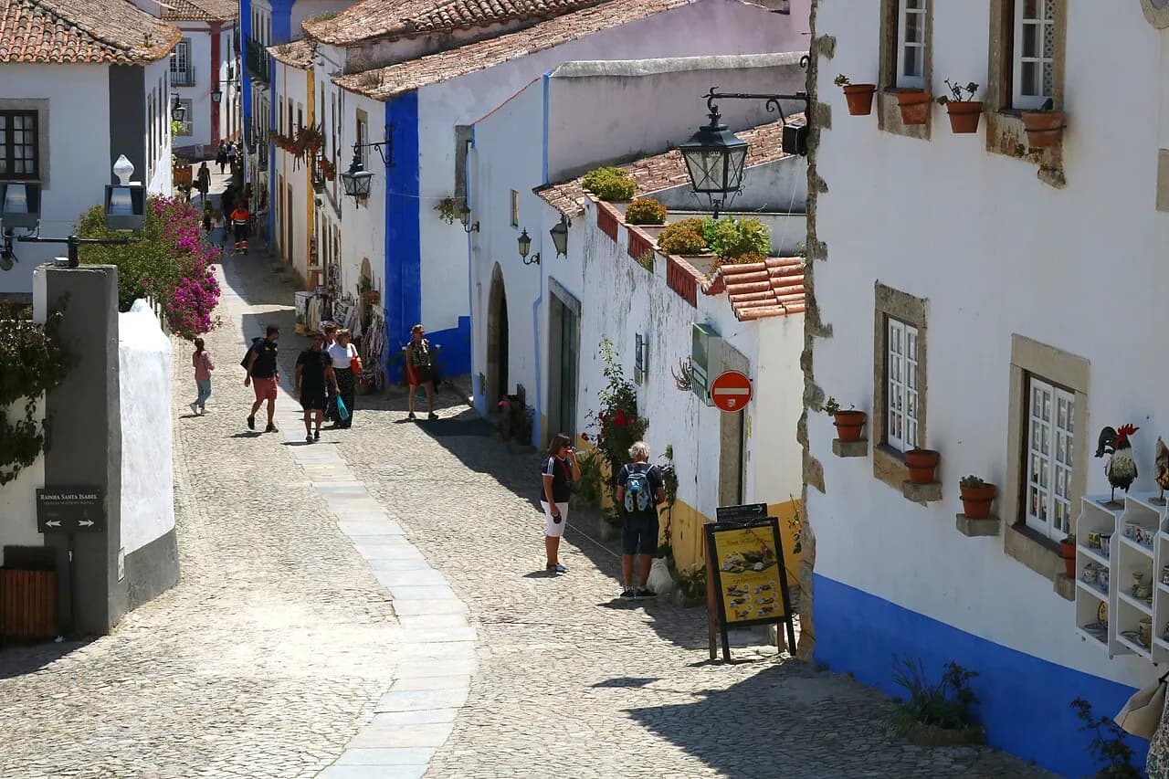 Calle empedrada de Óbidos con casas encaladas y zócalos azules